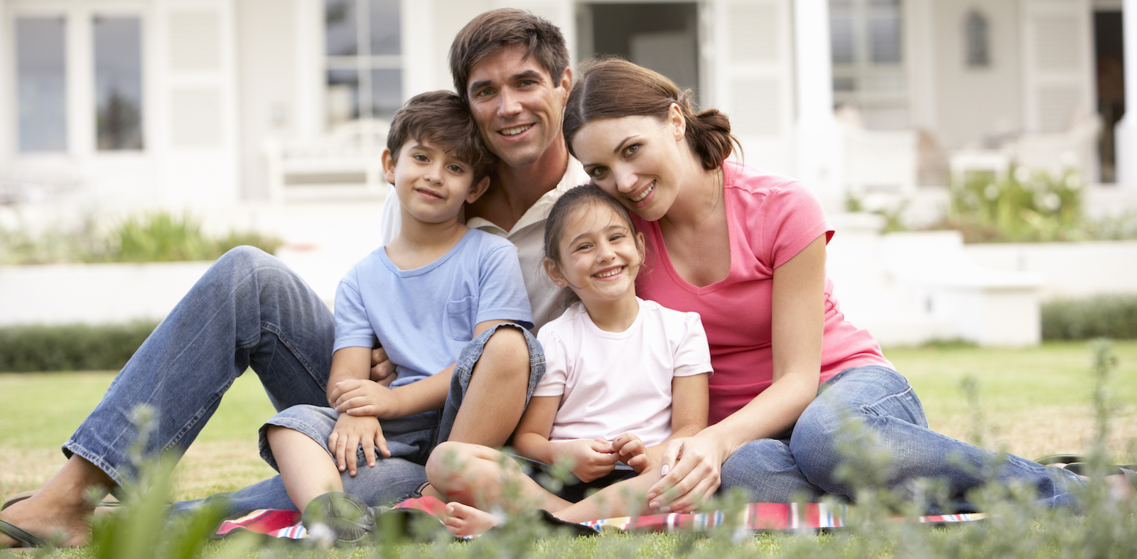 Family Sitting Outside House On Lawn